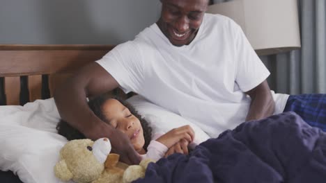 african american father waking up his daughter and laughing