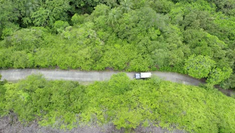 drone-shot-of-passing-jeet-with-kayak-on-concrete-road-between-forest