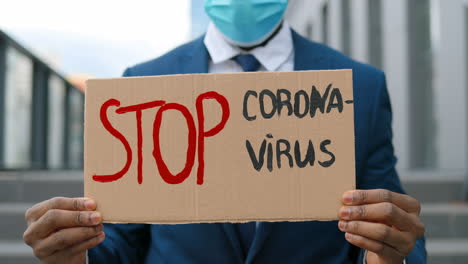 close-up view of sopt coronavirus" signboard holded by african american man in the street"