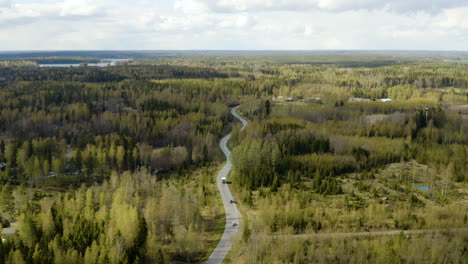 Aerial-view-overlooking-cars-and-a-truck-on-a-road-in-the-Porvoo-archipelago,-on-a-sunny,-spring-day,-in-the-Saaristo-of-Uusimaa,-Finland