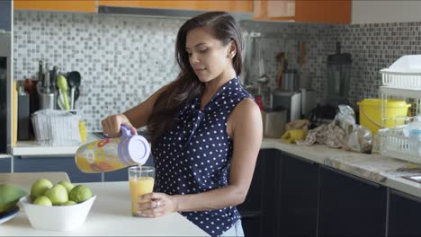 Encantadora-Mujer-Feliz-Bebiendo-Jugo-De-Naranja-Fresco-De-Pie-En-La-Cocina