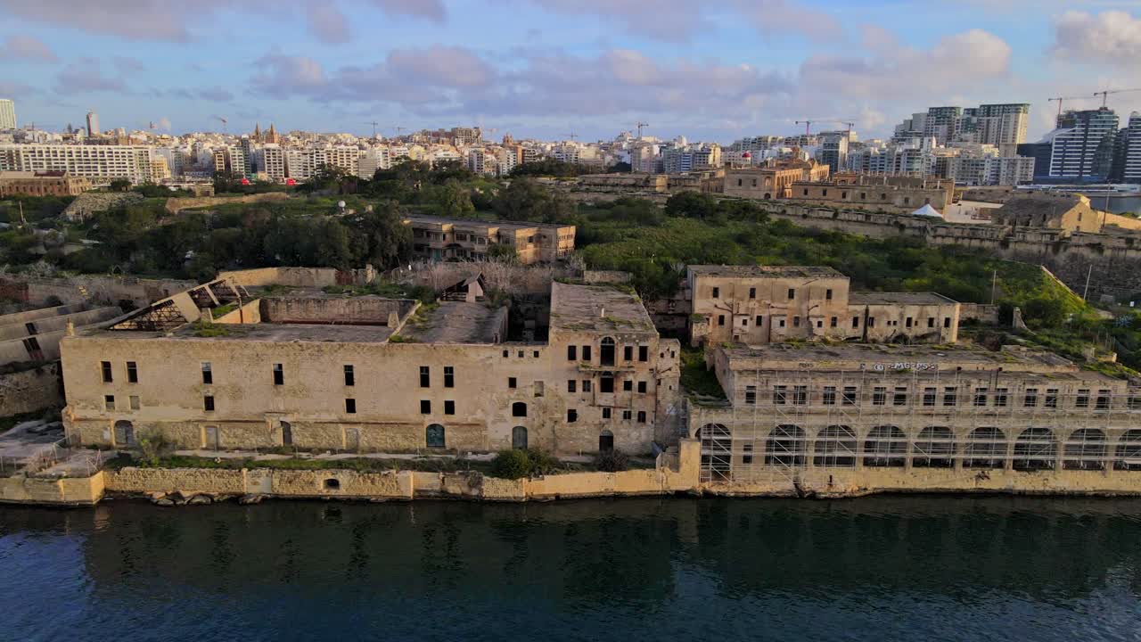 Vista aerea degli edifici abbandonati dell'ospedale Lazzaretto sull'isola di Manoel con il moderno skyline della città a Malta