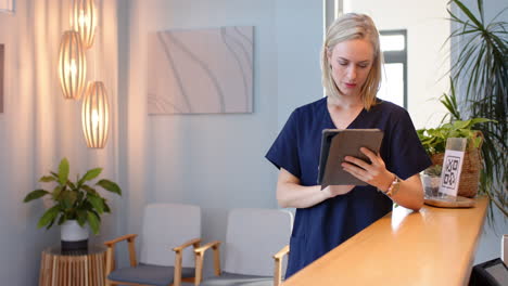 in medical clinic, female technician using tablet while standing at reception desk, copy space