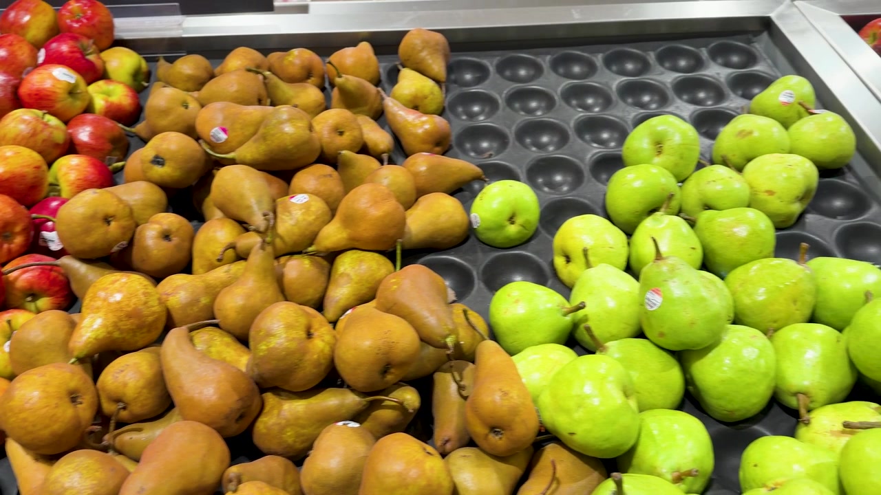 Bovenaf zwenkend beeld van verse appels en peren in de groente- en fruitafdeling van een supermarkt in de Blue Mountains.