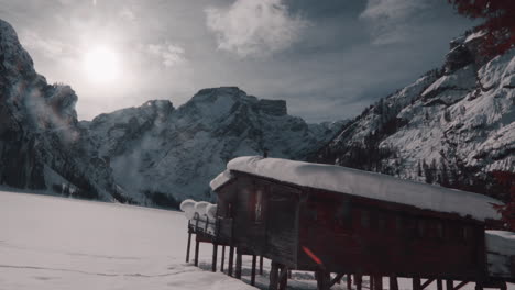 Boathouse-by-frozen-Lake-Braies-and-Dolomites-in-snow