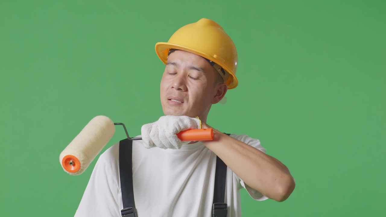 Close Up Of Asian Man Painter Wearing Safety Helmet Wiping The Sweat And Being Tired While Standing In The Green Screen Background Studio