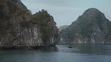 navegando más allá de pescadores locales más allá de impresionantes karsts de piedra caliza en la bahía de lan ha sobre las aguas tranquilas del mar, vietnam