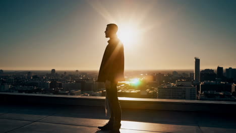 silhouette of a man contemplating the cityscape at sunset