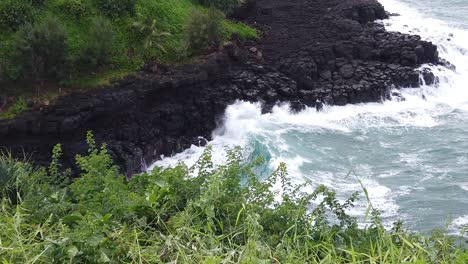 HD-120fps-Hawaii-Kauai-truck-left-to-right-greenery-to-reveal-overhead-view-of-waves-crashing-on-rocky-shoreline