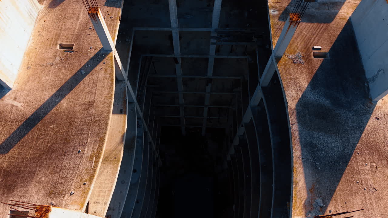 High angle view looking down into concrete building shaft. Looking down from a high floor into the central void or elevator shaft of an unfinished concrete building