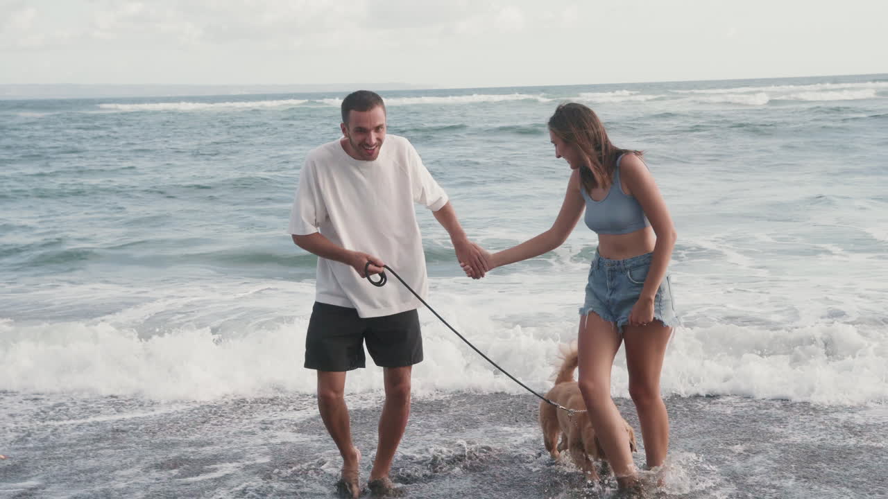 pareja y perro de pie en el mar
