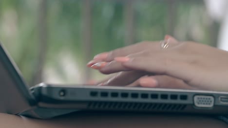 woman fingers with manicure and ring type on laptop closeup