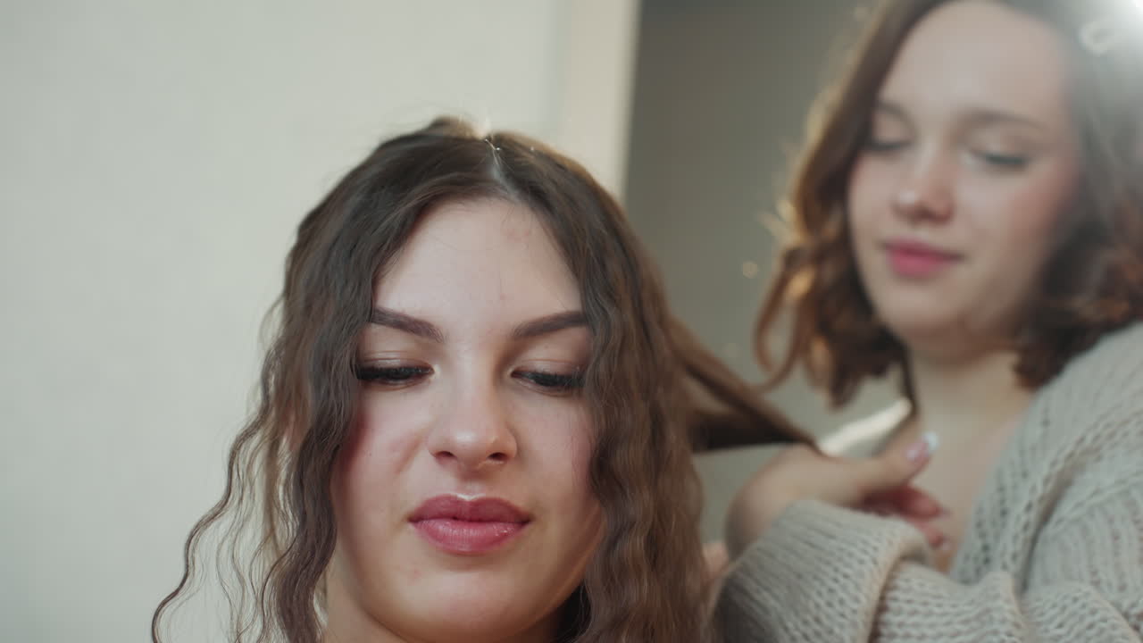 Amigas se peinan con confianza en interiores, escena informal en interiores de mujeres disfrutando de la belleza y la amistad, foto encantadora que captura a una mujer y a su amiga en un ambiente acogedor de cambio de imagen con sonrisas de confianza