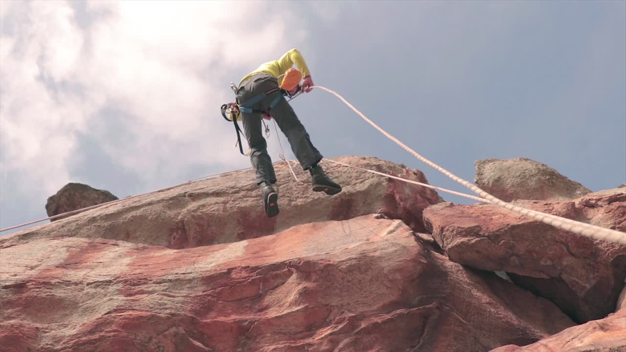 escalador masculino cayendo rápidamente desde una roca vertical