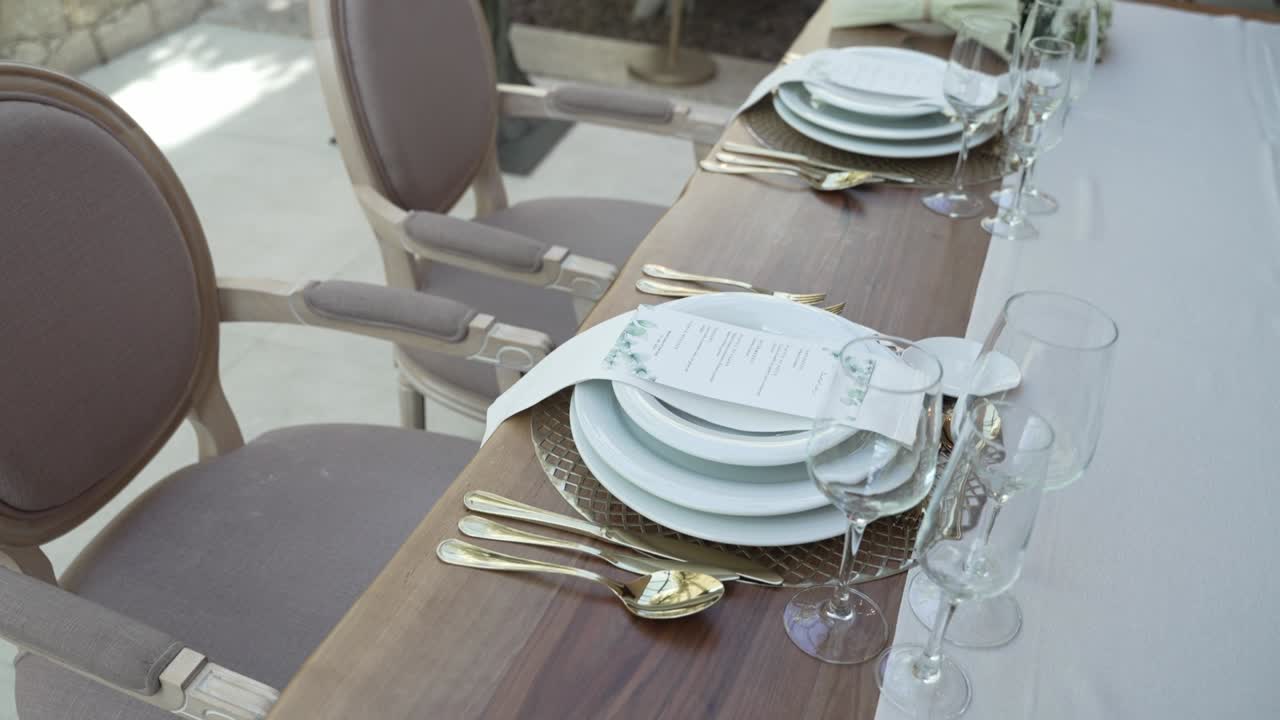 Elegant table arrangement with white floral centerpieces, tall candles, and stacked plates on a soft, neutral colored tablecloth