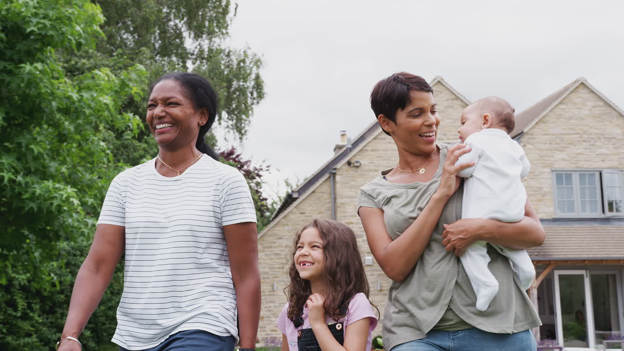 여러 세대 가족 의 딸 과 손녀 와 함께 집 에서 정원 에서  ⁇ 고 있는 어머니