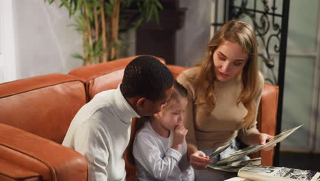 Thoughtful-girl-looks-at-old-family-photos-with-parents