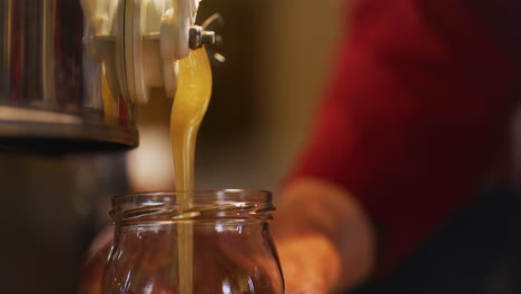 el apicultor vierte miel orgánica fresca en un frasco
