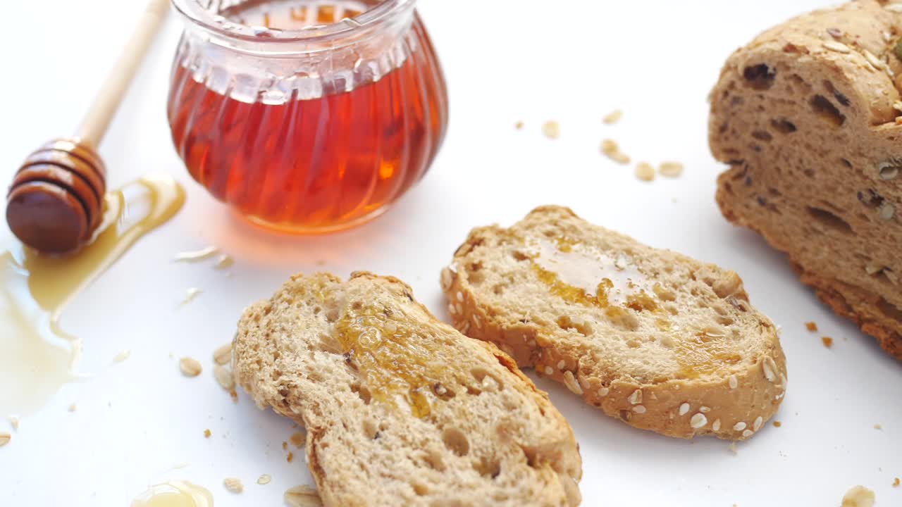 Sliced whole grain bread with oat flakes and honey on white