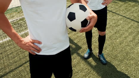 Close-Up-Of-Two-Unrecognizable-Football-Players-Standing-On-A-Street-Football-Pitch