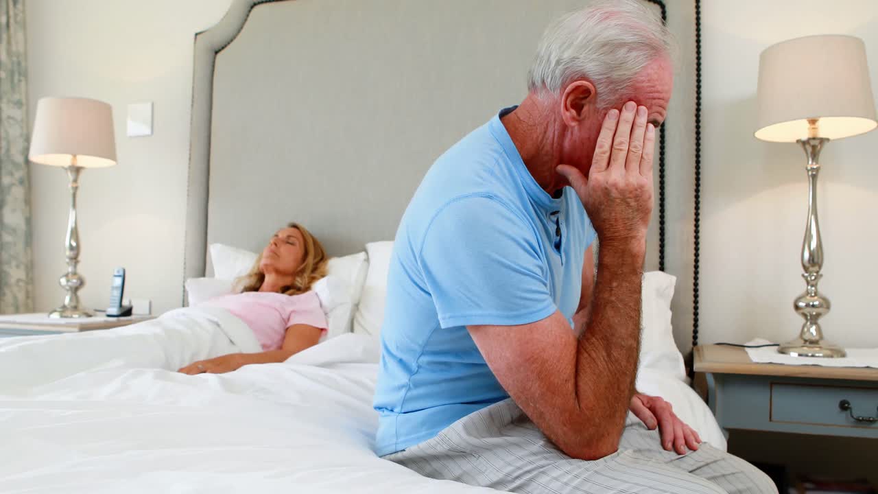 Uomo senior preoccupato che si siede nella camera da letto