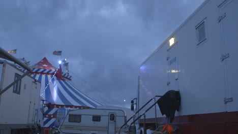 circus performers caravan in the foreground with circus tent at the back at night time