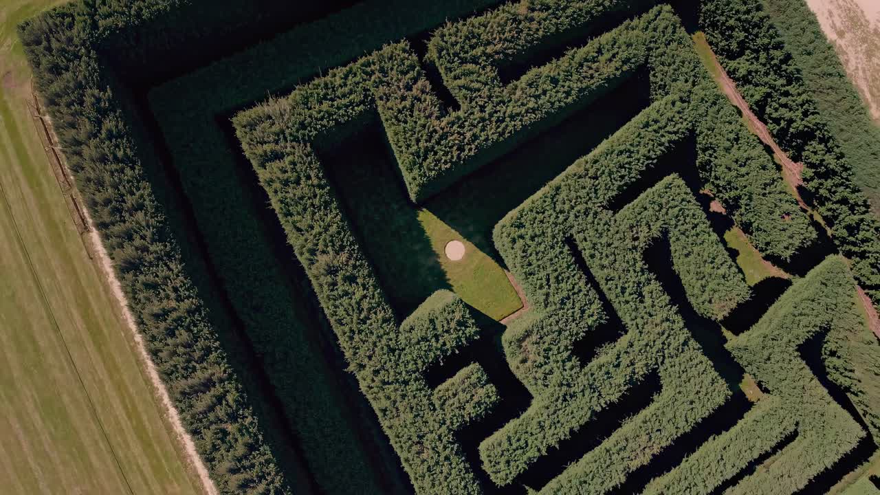 Aerial view of a lush green maze with intricate paths. The video captures the maze's geometric