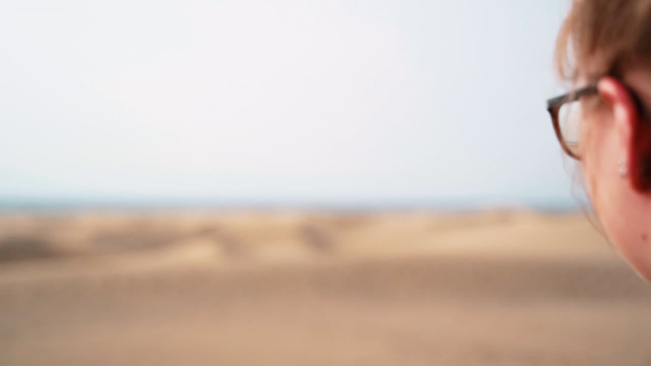 Ung pige nyder den smukke udsigt over sandørken, klitter og havvand på Gran Canaria, Spanien.
