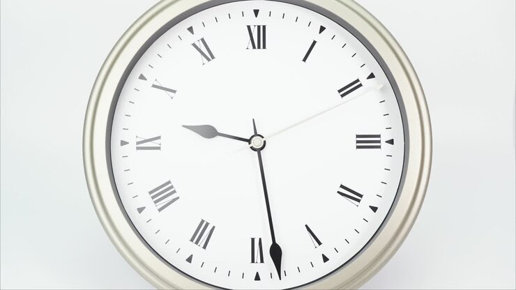 Time lapse silver wall clock tells the time from 3 minutes to 10 o'clock.