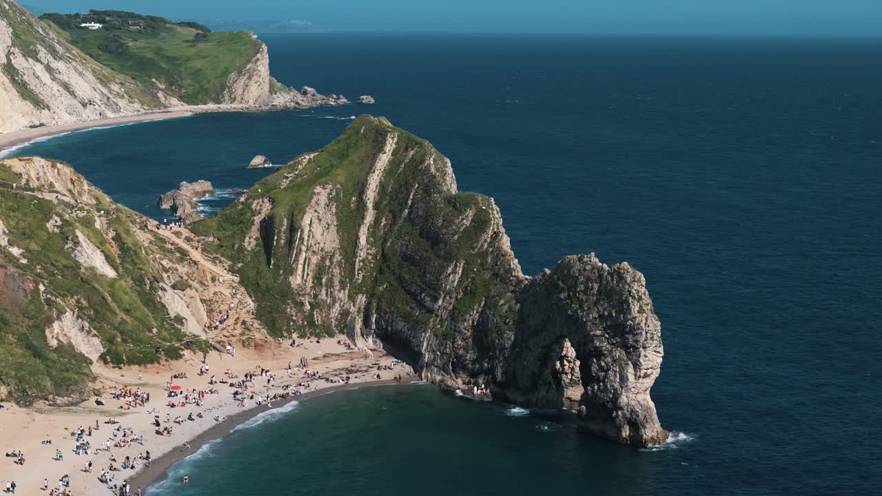 Wide orbit left above Durdle Door beach with birds flying below