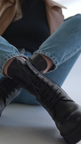 woman wearing black lace-up boots and jeans