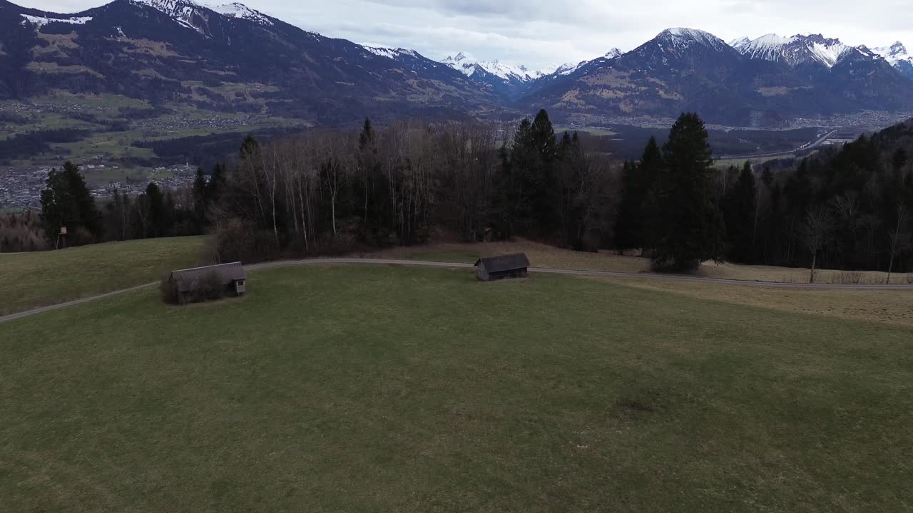 드론은 소나무 숲과 눈 인 산을 향해 어 니다. 오스트리아 네징의 도시 풍경을 볼 수 있습니다.