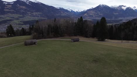 drone tilt up shot towards pine forest and snow capped mountains, aerial cityscape view over nenzing austria