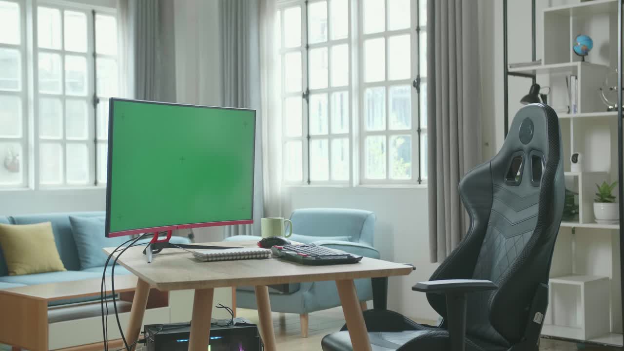 Green Screen Desktop Computer Next To The Notebook And A Cup Is On A Table With A Chair In The Working Room At Home.