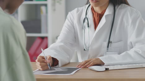 Female-Doctor-Or-Consultant-Wearing-White-Coat-Having-Meeting-With-Female-Patient-To-Discuss-Scans