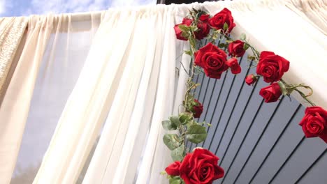 A-perimeter-of-red-roses-surrounds-a-doorway-of-white-cloth