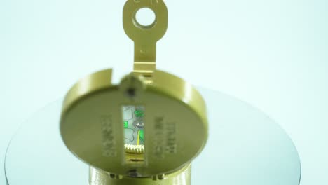 a close up shot of a golden retro opened compass on a reflecting rotating stand, 360 degrees, green arrows, studio lighting, slow motion, 4k video