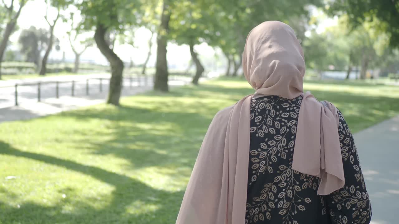 히자브 를 입은 여자 가 공원 에서 고 있다