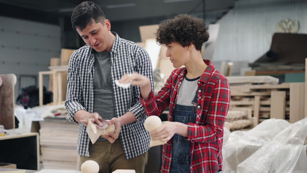 Two people working on wooden crafts in a workshop