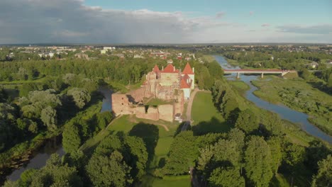 aerial flying away from bauska castle in latvia at golden hour, showing a tourist attraction