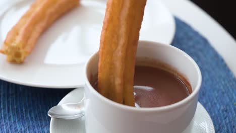 a slow-motion footage dipping and stiring spanish churros in hot chocolate sauce