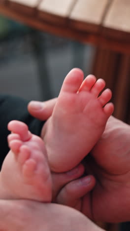 caucasian man clapping the tiny feet of a baby. close up. father plays with his adorable son. vertical video