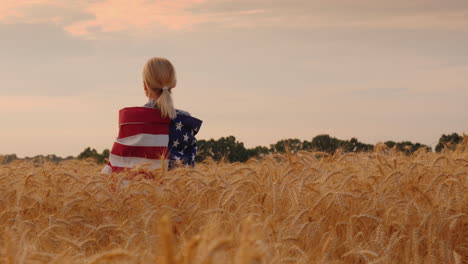 Frau-Mit-USA-Flagge-Auf-Den-Schultern-Steht-In-Einem-Weizenfeld-Draufsicht