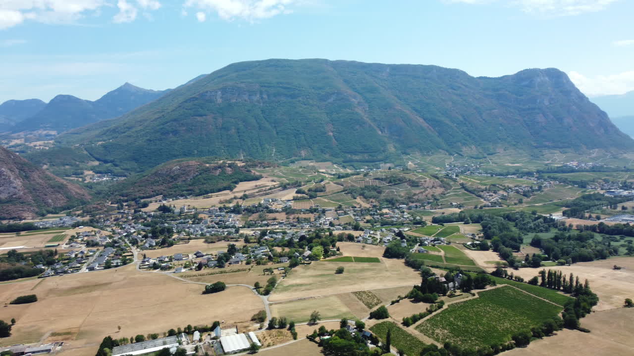 Aerial view of a picturesque valley with mountains, village, and vineyards