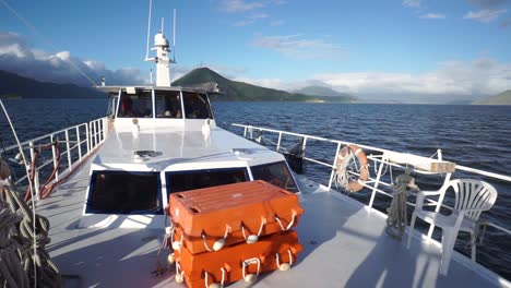 front deck of fishing and cockpit with crew inside and beautiful sunny scenery in background