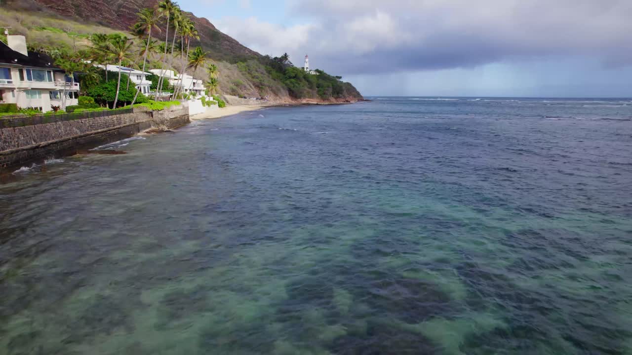 imágenes de drones a lo largo de la costa de oahu, hawai, pasando por el faro de diamond head, a través del océano pacífico azul claro y las playas de arena a lo longo de los escarpados acantilados de diamond head.