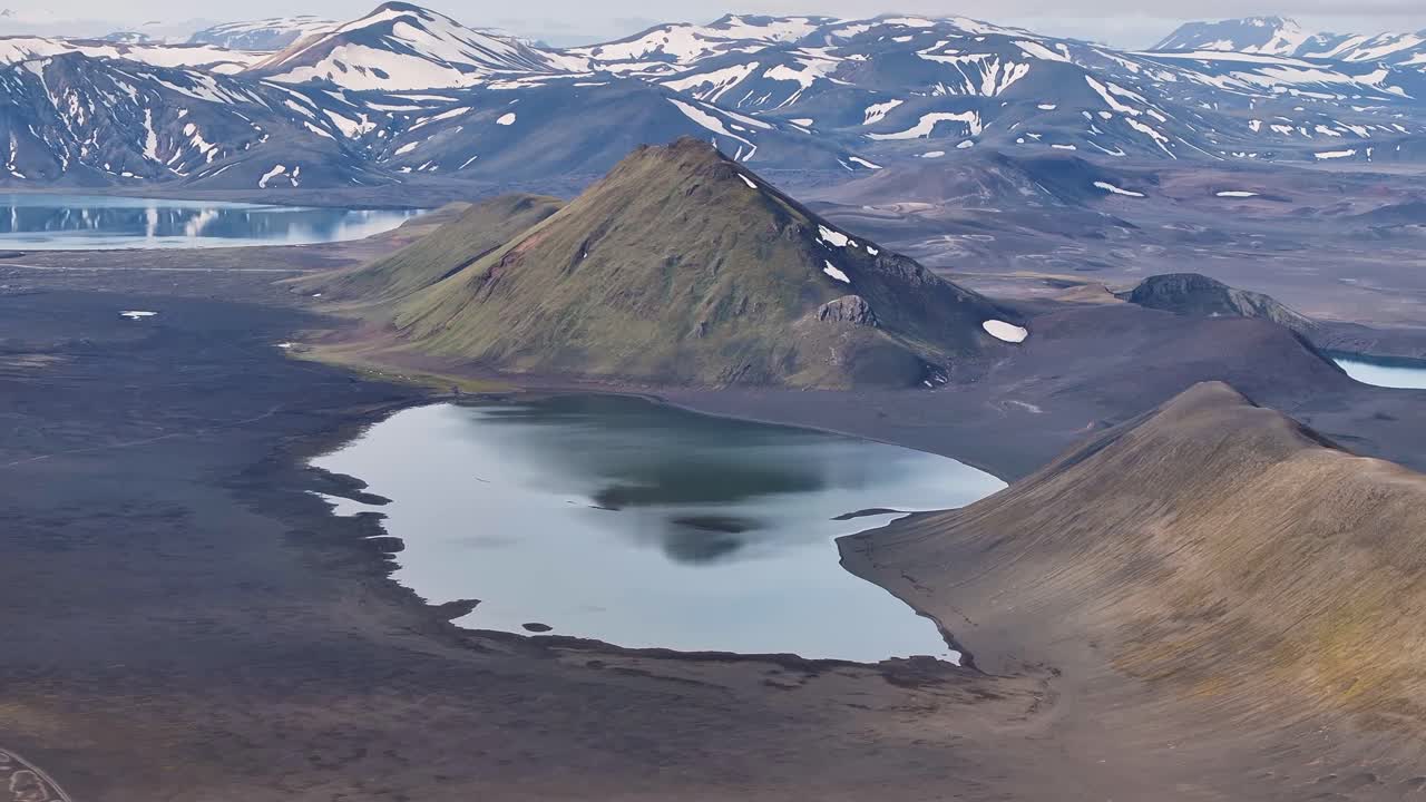 Icelandic lake in highlands of Iceland. Snowy mountain peaks in background. Sunny day at daylight. Aerial wide shot. River delta floating