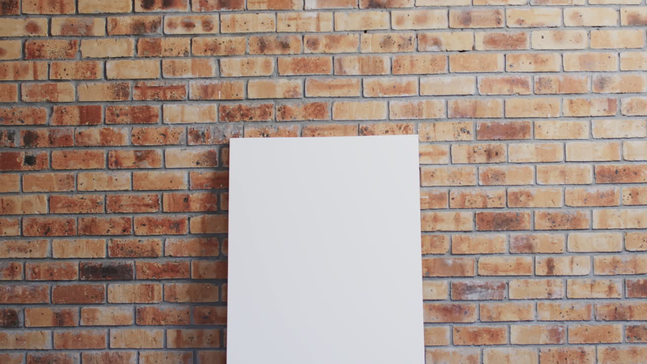 Video of white canvas sign with copy space on floor against brick wall background
