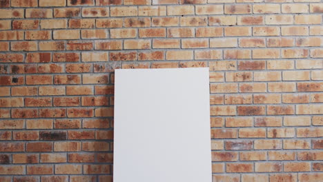 Video of white canvas sign with copy space on floor against brick wall background