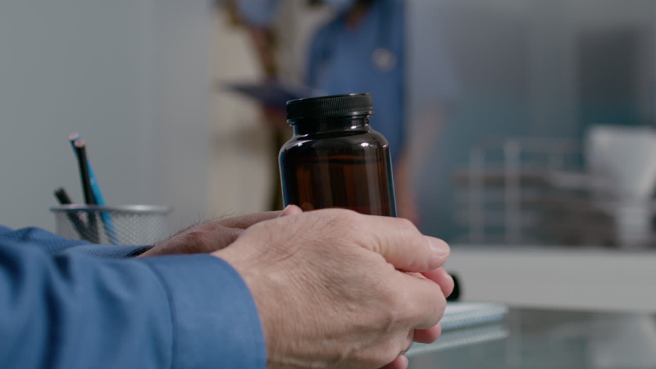 Male physician explaining medicine in bottle of pills to old man